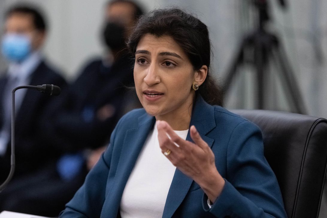 Lina Khan fait des gestes tout en parlant devant un petit microphone lors d